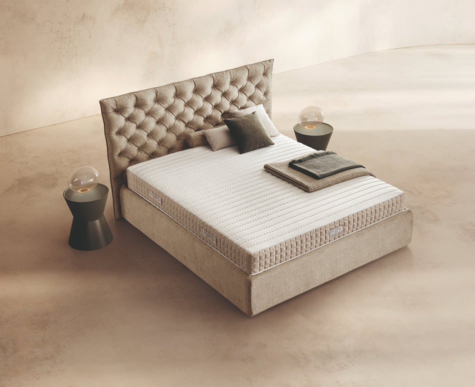 Materasso Dream Fold posizionato su un letto in ambiente neutro con sopra cuscini e scaldapiedi warmie