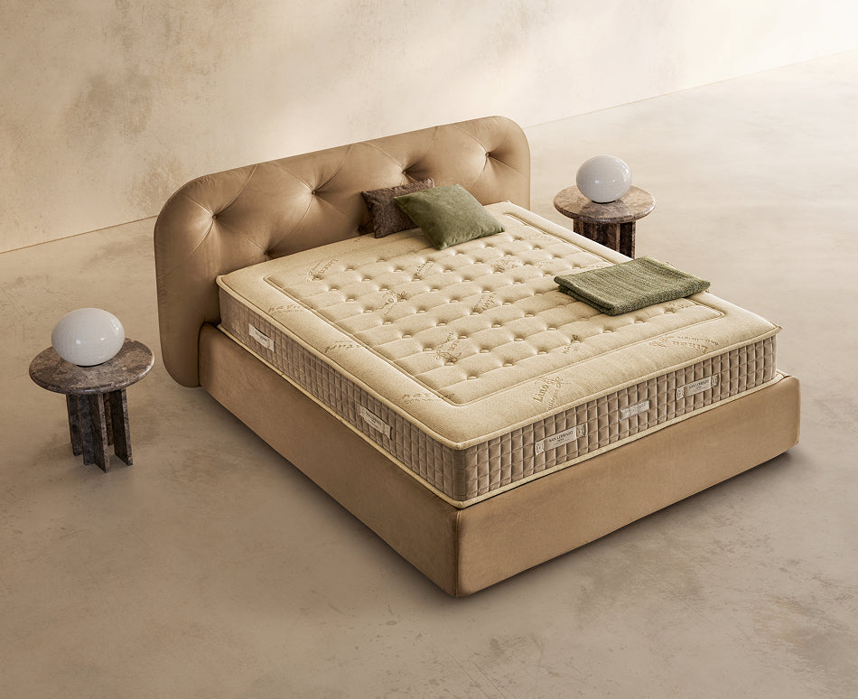 Materasso Green Bio Mind posizionato su un letto in ambiente neutro con sopra cuscini e scaldapiedi warmie