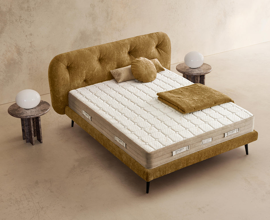 Materasso Pocket Fresh posizionato su un letto in ambiente neutro con sopra cuscini e scaldapiedi warmie