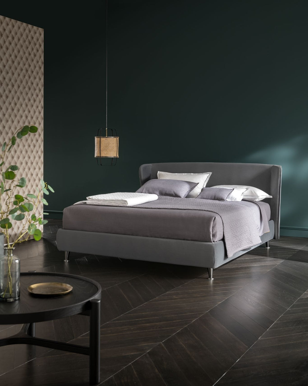 Letto imbottito grigio in una camera dai toni verdi
