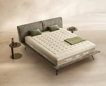 Materasso Aurora Latex posizionato su un letto in ambiente neutro con sopra cuscini e scaldapiedi warmie