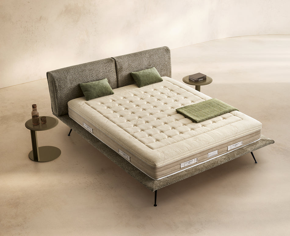 Materasso Aurora Latex posizionato su un letto in ambiente neutro con sopra cuscini e scaldapiedi warmie