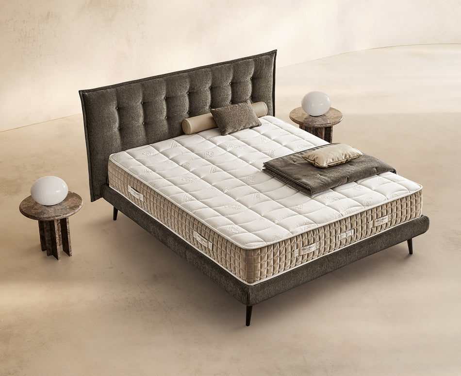 Materasso Bilatex Memory posizionato su un letto in ambiente neutro con sopra cuscini e scaldapiedi warmie