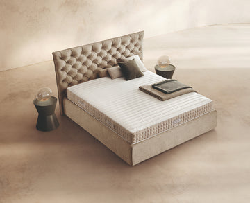 Materasso Dream Fold posizionato su un letto in ambiente neutro con sopra cuscini e scaldapiedi warmie