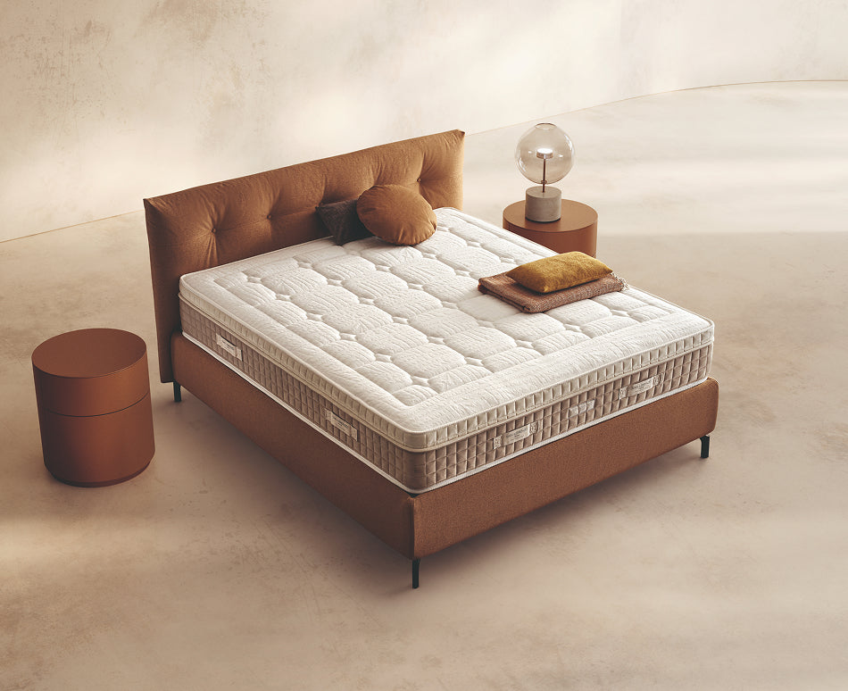 Materasso Pocket Mind posizionato su un letto in ambiente neutro con sopra cuscini e scaldapiedi warmie