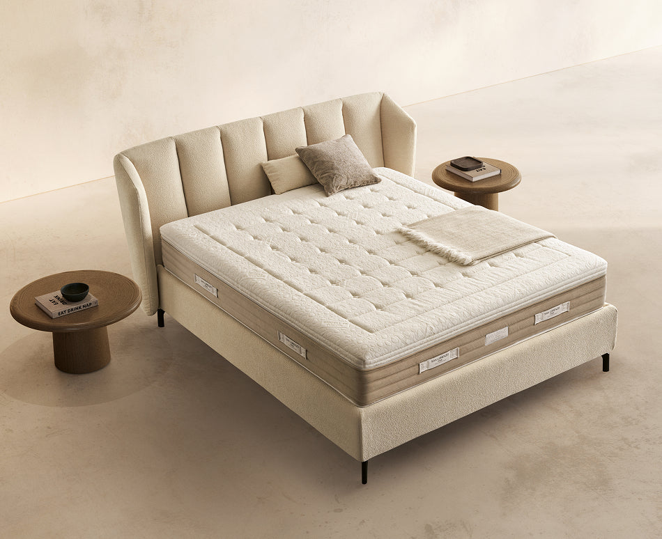 Materasso Prestige Memory posizionato su un letto in ambiente neutro con sopra cuscini e scaldapiedi warmie