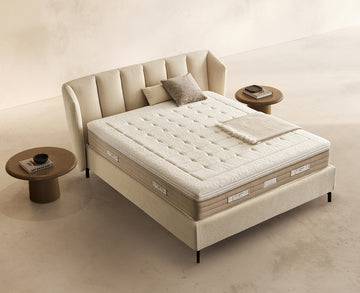 Materasso Prestige Memory posizionato su un letto in ambiente neutro con sopra cuscini e scaldapiedi warmie