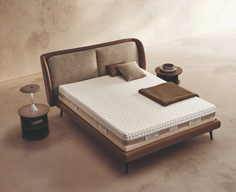 Materasso Space Memory posizionato su un letto in ambiente neutro con sopra cuscini e scaldapiedi warmie